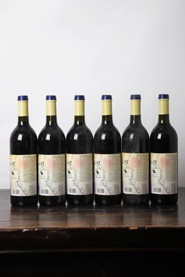 six bouteilles de vin sont alignées sur une table en bois