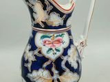 a blue and white pitcher with a flower design on it