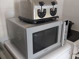 un four grille-pain posé sur un micro-ondes dans une cuisine
