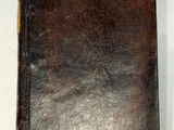 un vieux livre en cuir marron posé sur une table blanche