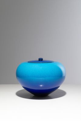 une image représentant un vase bleu posé sur une table blanche