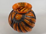 a small orange vase sitting on a white surface
