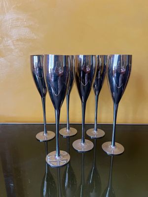 quatre verres à vin argentés posés sur une table en verre