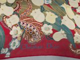 a close up of a red and green scarf with white flowers on it