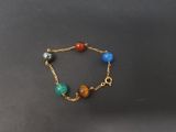 a close up of a gold chain bracelet with multi colored beads