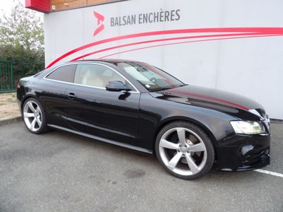 une voiture noire garée devant un immeuble, sur un parking