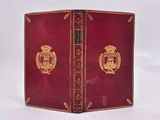 an old book with a red cover with a gold emblem on it