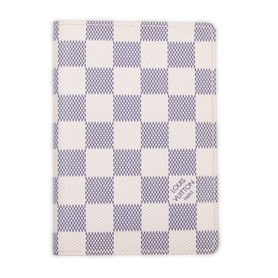 a white and blue checkered passport case sitting on top of a white surface