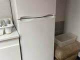a white refrigerator in the corner of a small kitchen