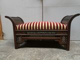 un banc en bois sur lequel est posé un coussin rayé