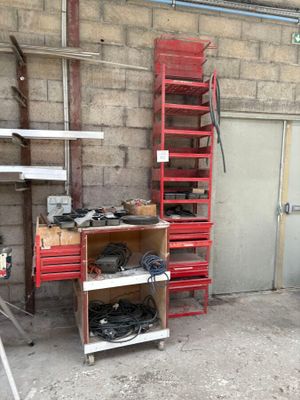 une étagère rouge sur laquelle sont posés des outils, dans un garage