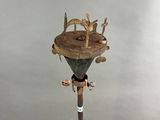 une sculpture représentant un homme sur un poteau sur lequel est perché un oiseau