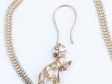 a close up of a silver necklace with a mouse on it