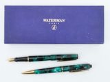 a pair of fountain pens sitting on top of a blue box