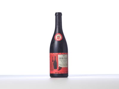 La bouteille de vin est posée sur une table devant un fond blanc.