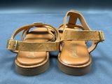 the gold sandals are on a blue surface with a blue background