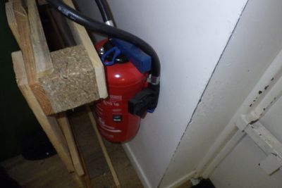 un extincteur fixé au mur à côté d'une borne d'incendie