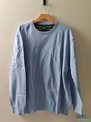 une chemise bleue à manches longues suspendue à un cintre contre un mur