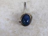a close up of a blue stone pendant on a white surface