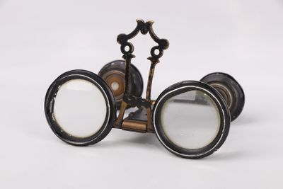 une paire de jumelles anciennes avec une loupe, sur fond blanc