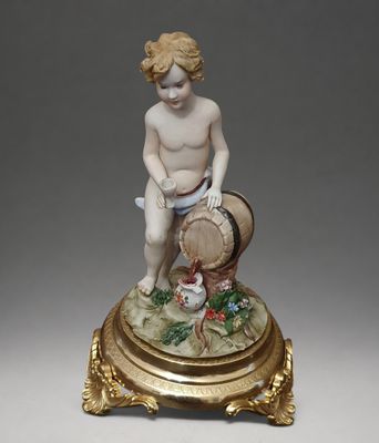 an antique figurine of a boy with a basket of fruit