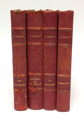 trois livres rouges sont empilés sur une surface blanche