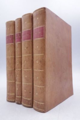 three old books are stacked on top of each other on a white surface