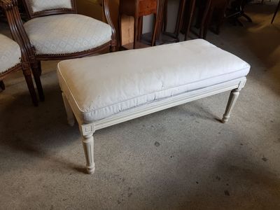 un banc blanc avec un coussin posé dessus, au milieu d'une pièce