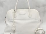 white leather handbag with strap and wrist strap on white background