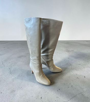 un gros plan sur une paire de bottes blanches posées sur un sol en béton