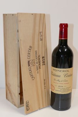 une bouteille de vin dans un coffret en bois à côté d'une bouteille de vin