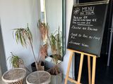 a chalk board with a menu written on it in front of some plants