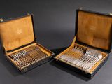 two open cases with silverware in them on a black surface