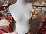 a mannequin on a stand in a room full of furniture