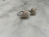 a pair of silver earrings on a marble surface