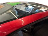 a close up of a red car with a green sticker on the window