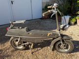 un petit scooter garé sur le gravier