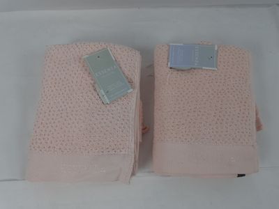 une paire de serviettes roses, encore étiquetées, posées sur une surface blanche