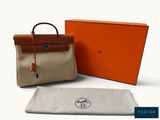 un gros plan sur un sac et une serviette posés sur une surface blanche