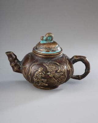 a brown teapot with a dragon design on it