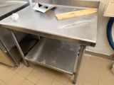 une table de travail en acier inoxydable sur laquelle est posée une planche à découper