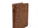 an old book with a brown cover sitting on top of a white surface
