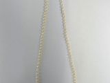 un gros plan d'un collier blanc orné de perles sur fond blanc