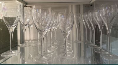 many empty wine glasses lined up on a glass shelf