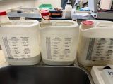 three containers of milk sitting on a counter next to a sink