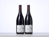 two bottles of red wine sitting on top of a table
