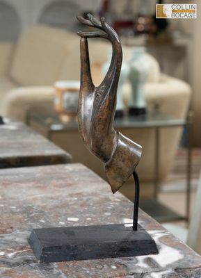 une sculpture en bronze représentant un oiseau posée sur une table en marbre