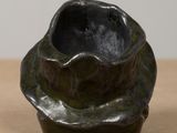a black vase sitting on a table with a white wall in the background
