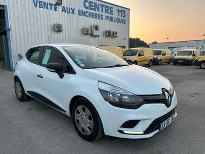 une voiture blanche garée devant un immeuble, avec d'autres voitures en arrière-plan