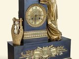 une statue représentant une femme assise au sommet d'une horloge bleue et dorée